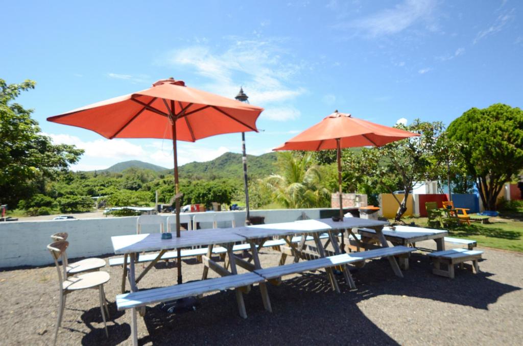 a picnic table with two red umbrellas and chairs at Ciao House B&B in Kenting