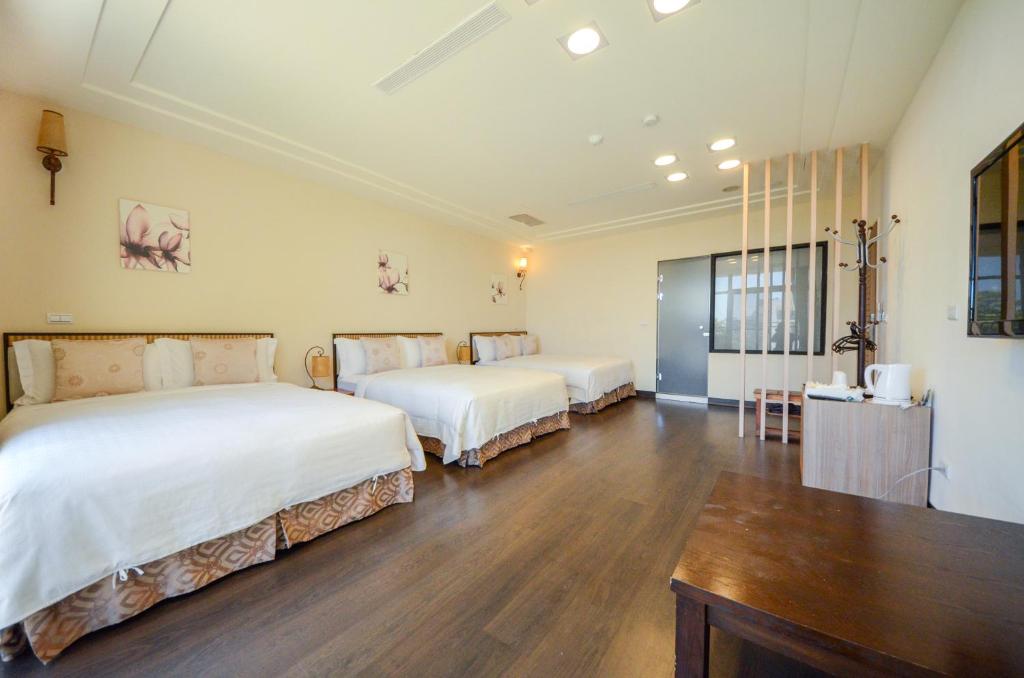 two beds in a room with a wooden floor at Ciao House B&B in Kenting