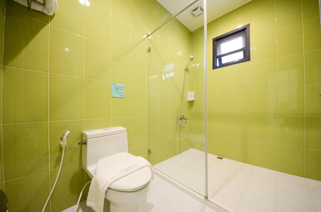 a green bathroom with a toilet and a shower at Ciao House B&B in Kenting