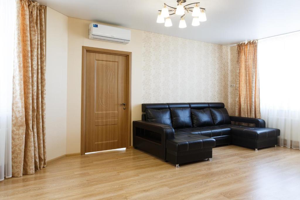 a living room with a black leather couch and a door at Nataliya's flat apartments Shcherbakovskiy pereulok 7 in Kazan