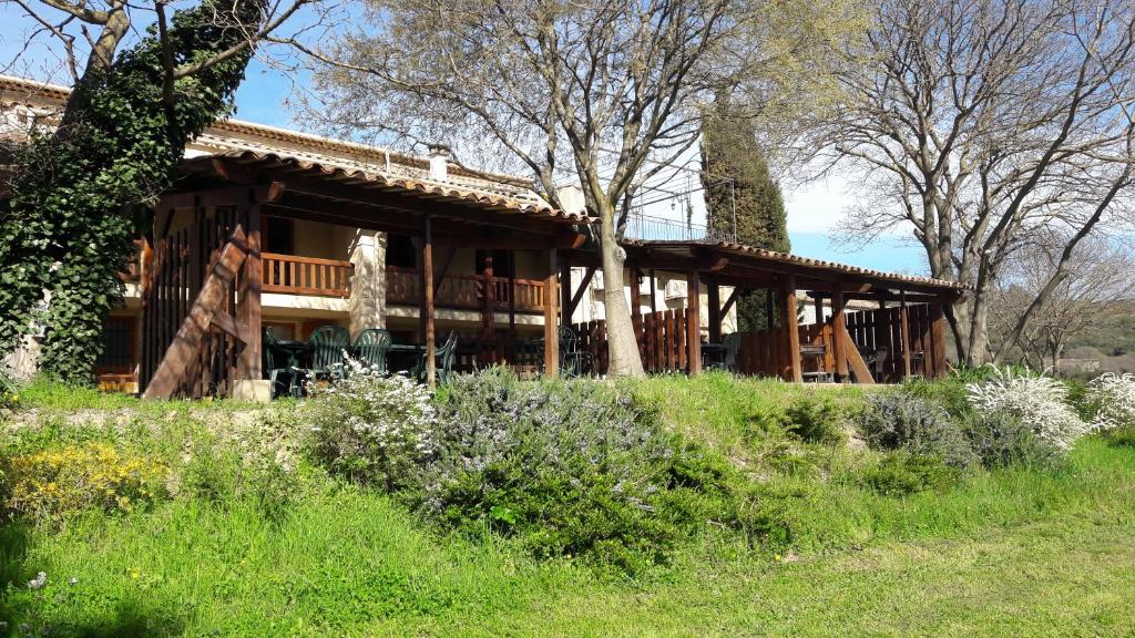 Cette grande maison en bois est entourée d'une terrasse couverte. dans l'établissement Le Mas De Roux, à Bragassargues