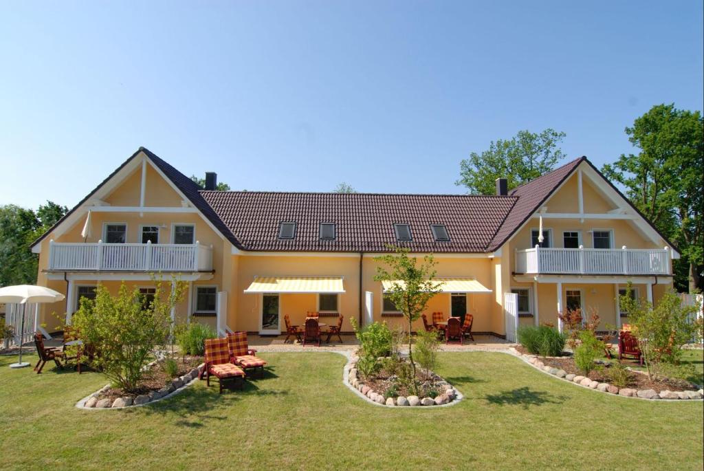 ein Haus mit einem Garten mit Stühlen und Tischen in der Unterkunft Eulenhof Rügen in Putbus