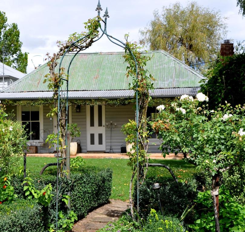 een oud huis met een groen dak en een tuin bij Drayshed cottage in Blayney