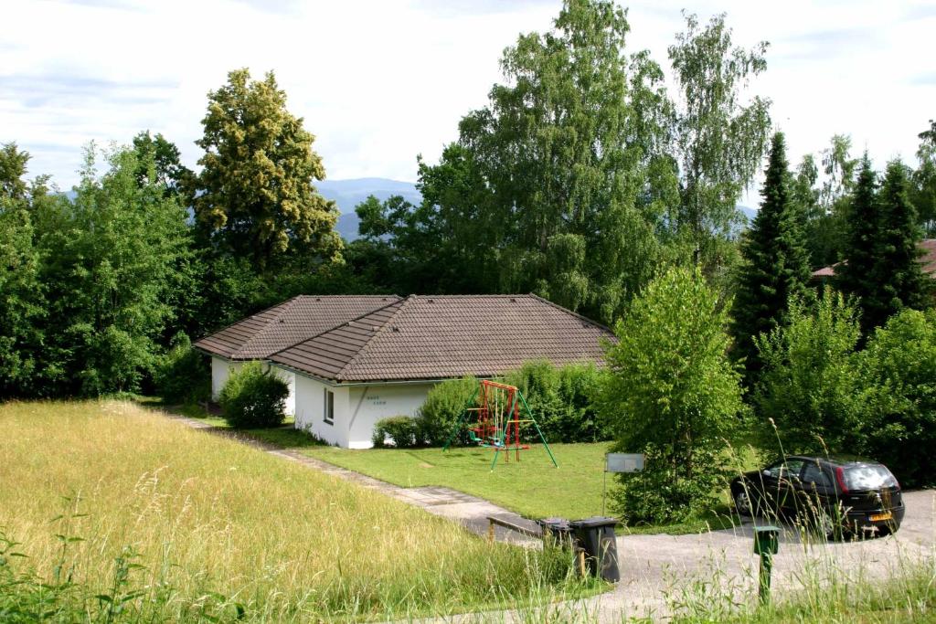 a small white house with a playground in the yard at Bungalows Karin in Sankt Kanzian