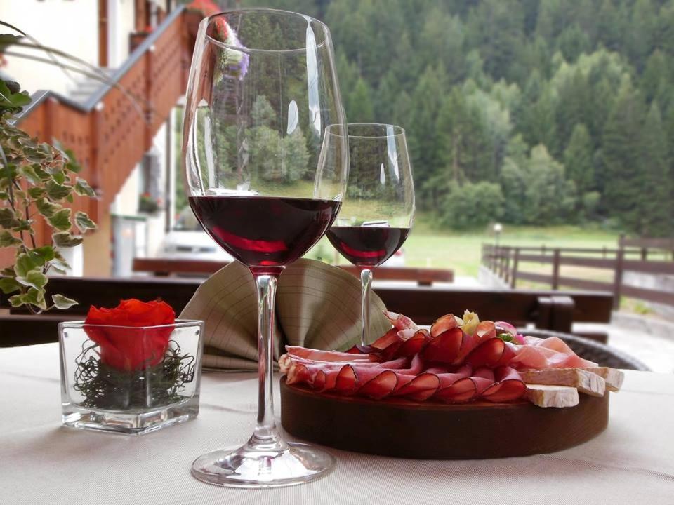 twee glazen wijn en een bord eten op tafel bij Rosengarden Alpine Residence in Valdidentro