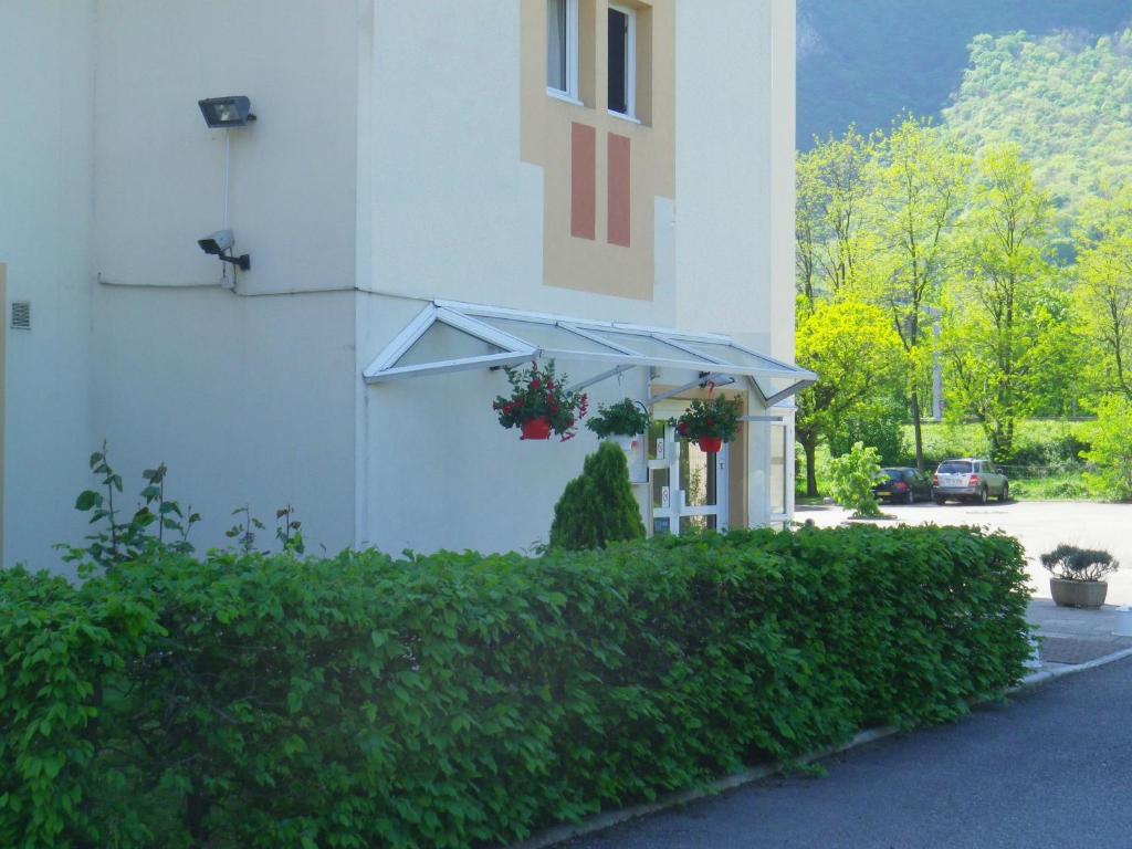 un bâtiment avec des plantes en pot sur son côté dans l'établissement Hotel Amys Voreppe, à Voreppe