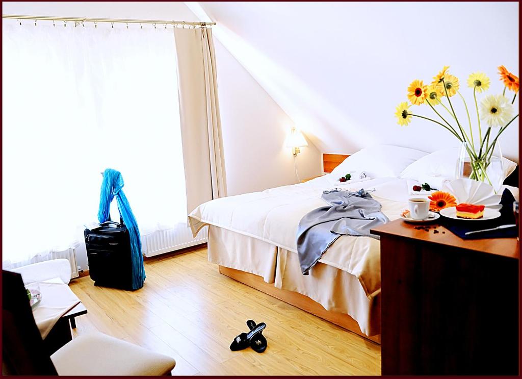 a bedroom with a bed and a table with a vase of flowers at Apartamenty Pod Lwem in Świdnica