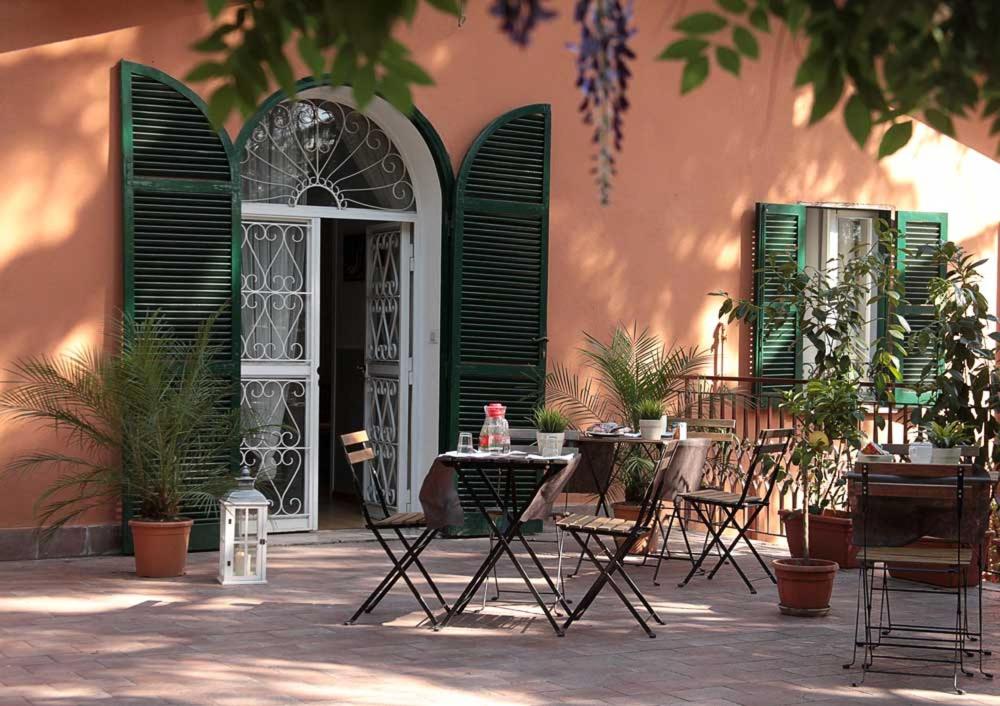Affittacamere Villa Drusilla في روما: فناء في الهواء الطلق مع طاولات وكراسي ونباتات