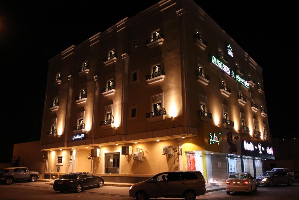 un edificio con coches aparcados delante de él por la noche en الضوء الخافت للشقق المخدومه, en Al Kharj