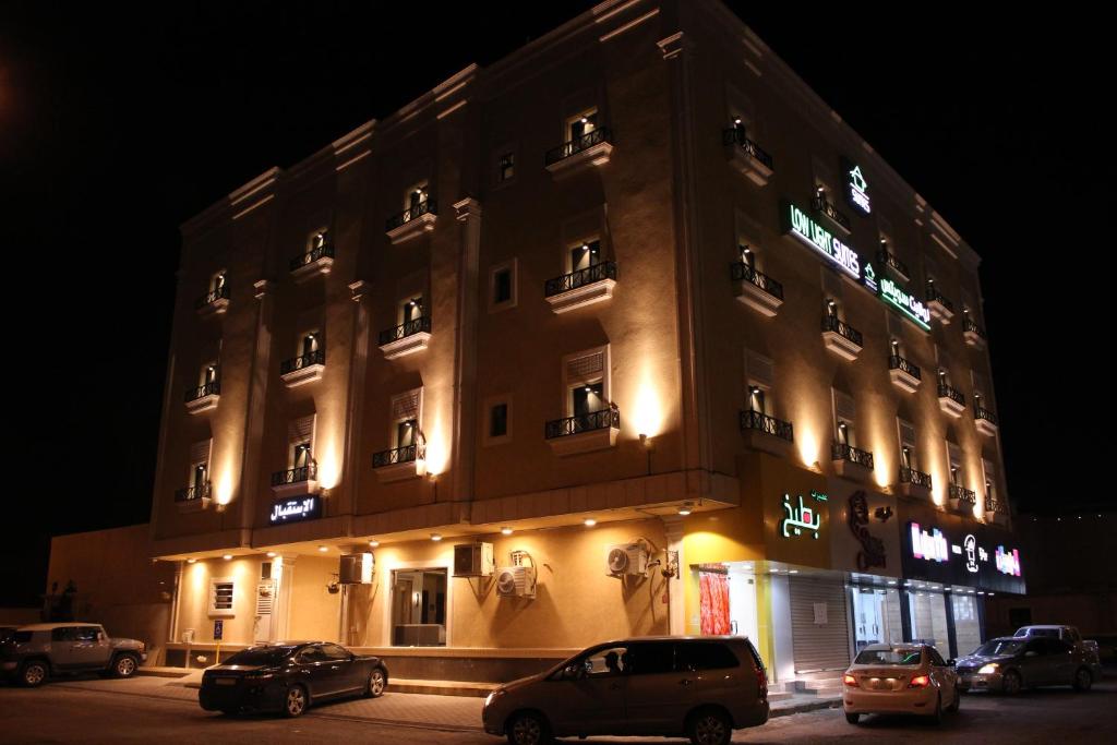 a building with cars parked in front of it at night at Low Light Suites in Al Kharj