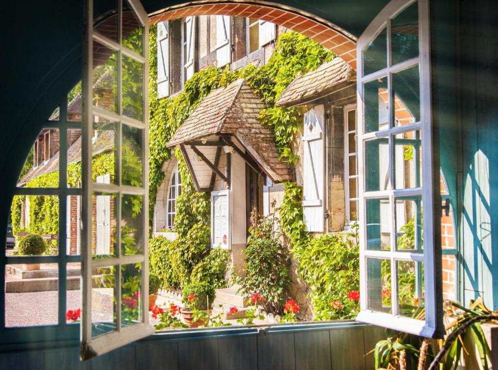 an open window looking out at a house with flowers at L'Ile de Sees in Macé