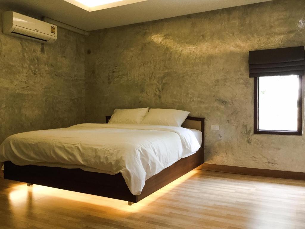 - une chambre avec un lit dans une pièce dotée d'une fenêtre dans l'établissement Nai Suan Inn, à Ban Doem Bang