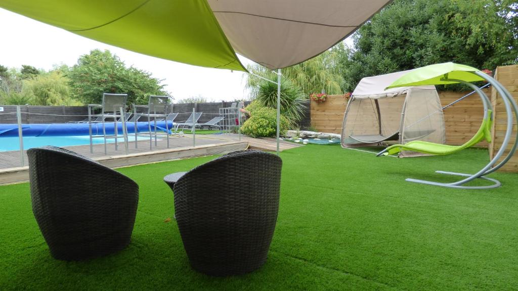 eine Liegewiese mit 2 Stühlen, einem Zelt und einem Pool in der Unterkunft Le Parasol in Ars-en-Ré