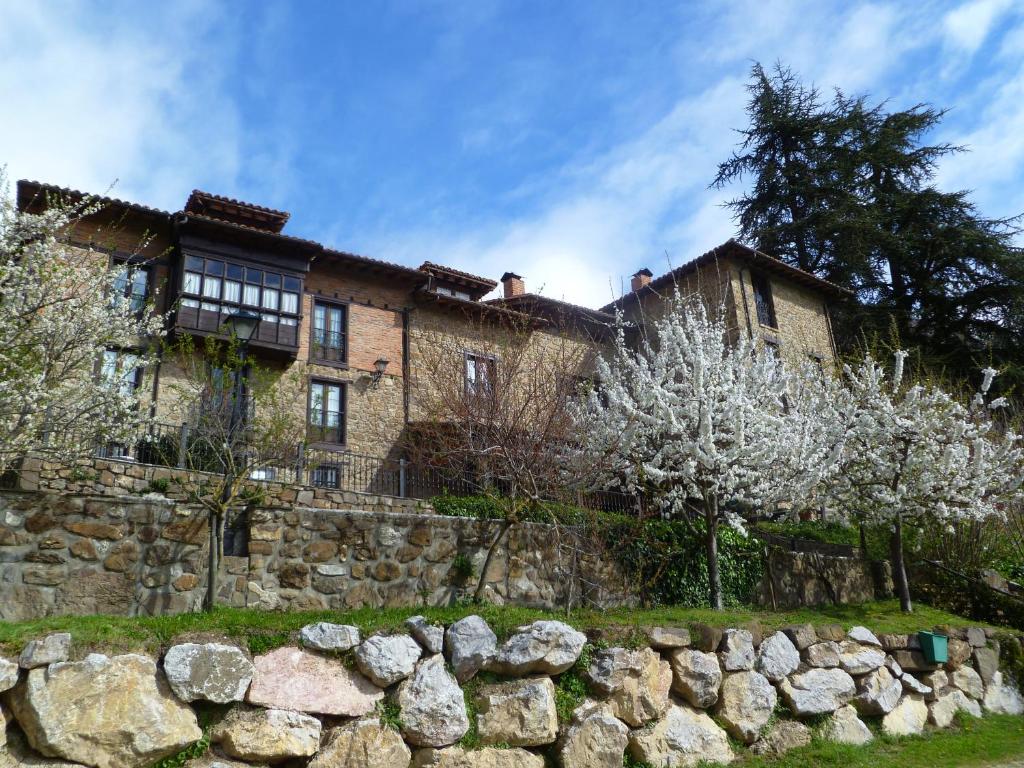 una antigua casa de ladrillo con una pared de piedra y árboles en La Posada de Viñón - Casa Reda en Viñón