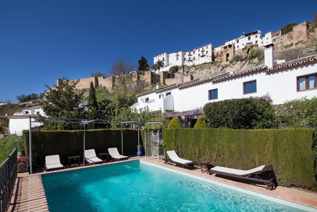 a swimming pool with lounge chairs next to a building at Alavera de los Baños in Ronda