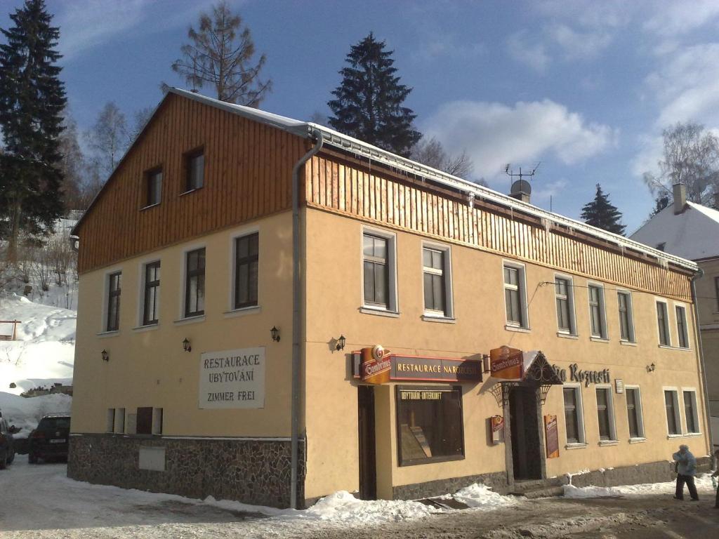 un vieux bâtiment avec un magasin dans la neige dans l'établissement Penzion Na Rozcestí, à Janov nad Nisou
