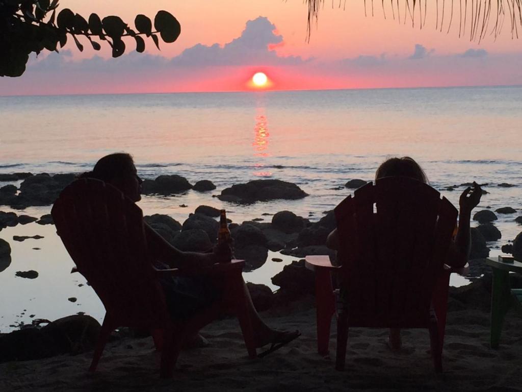 dos personas sentadas en sillas en la playa viendo la puesta de sol en La Princesa de La Isla, en Isla Grande del Maíz