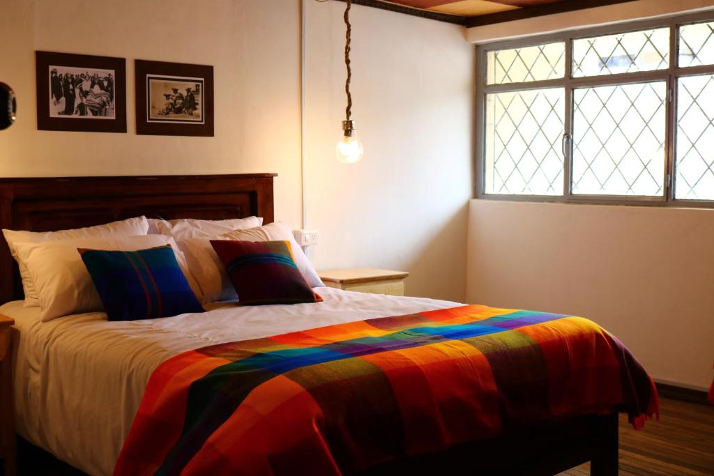 a bedroom with a bed with a colorful blanket at Hospedaje Los Ponchos in Otavalo