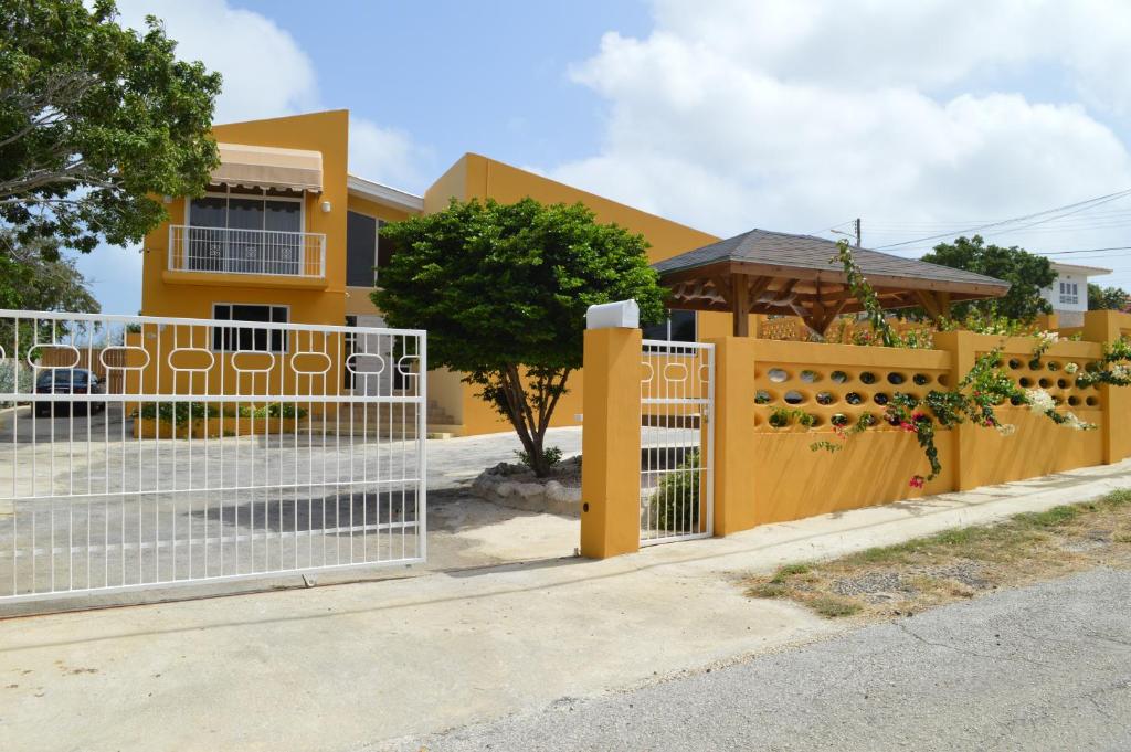 a fence in front of a yellow house at Eve's Residence in Willemstad