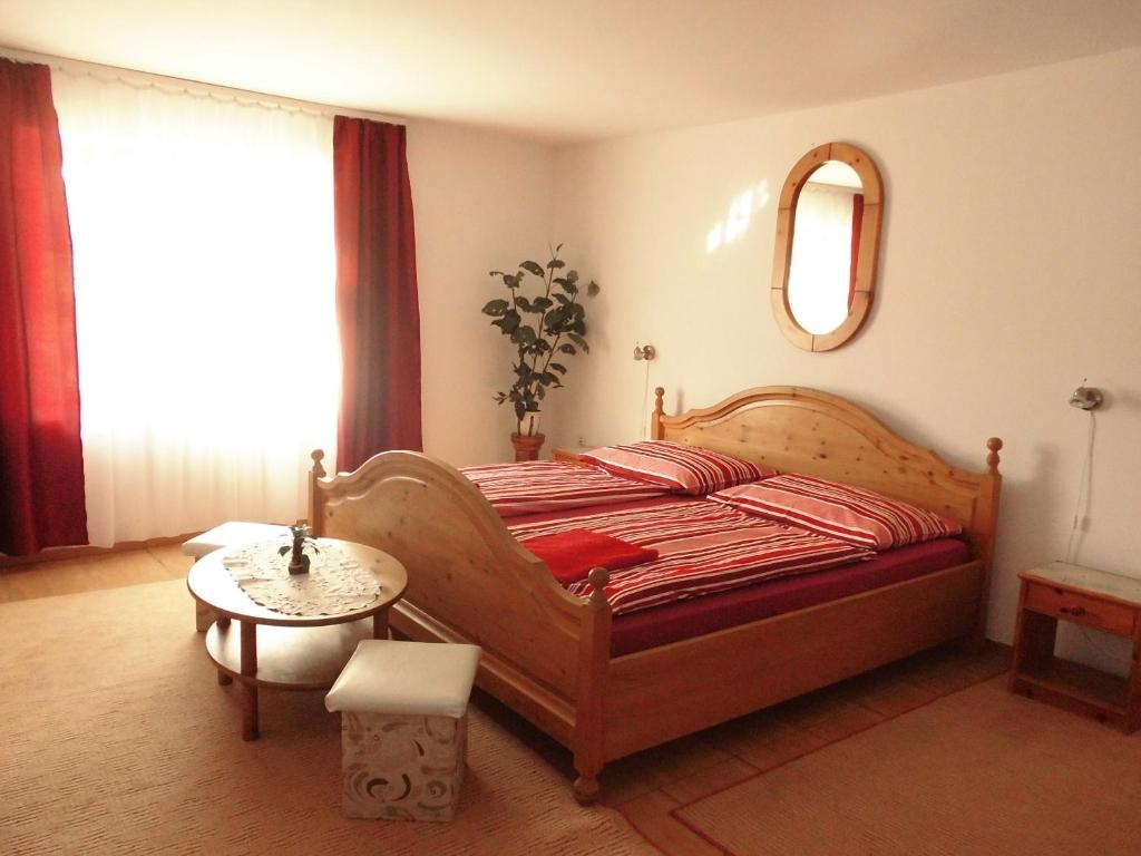 a bedroom with a bed and a table and a mirror at Fenyves Apartman in Sárospatak