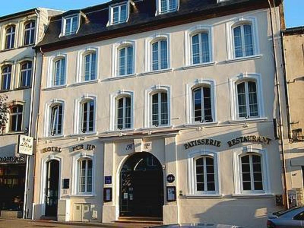 un grand bâtiment blanc avec une porte dans une rue dans l'établissement Logis Hotel de Paris, à Saint-Avold