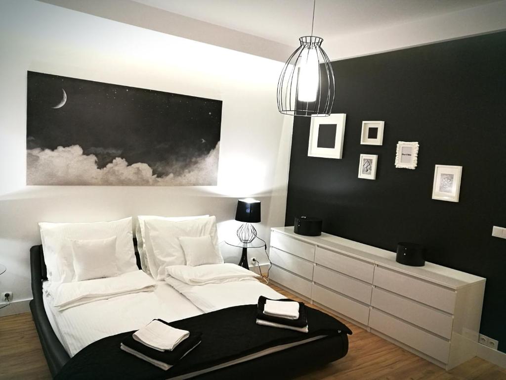 a bedroom with a white bed with a black wall at Black&White Apartment- Wierzbowa 5 in Poznań
