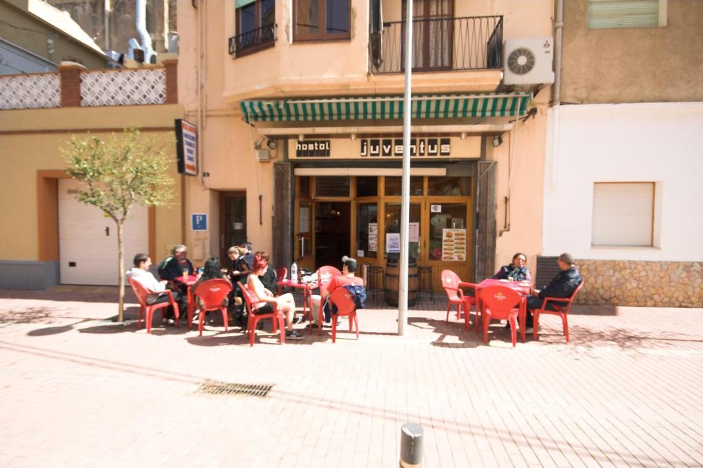 un groupe de personnes assises sous les chaises devant un bâtiment dans l'établissement Hostal Juventus, à Portbou