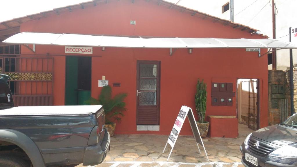 une maison rouge avec un panneau devant elle dans l'établissement Suítes São Judas, à Pirenópolis