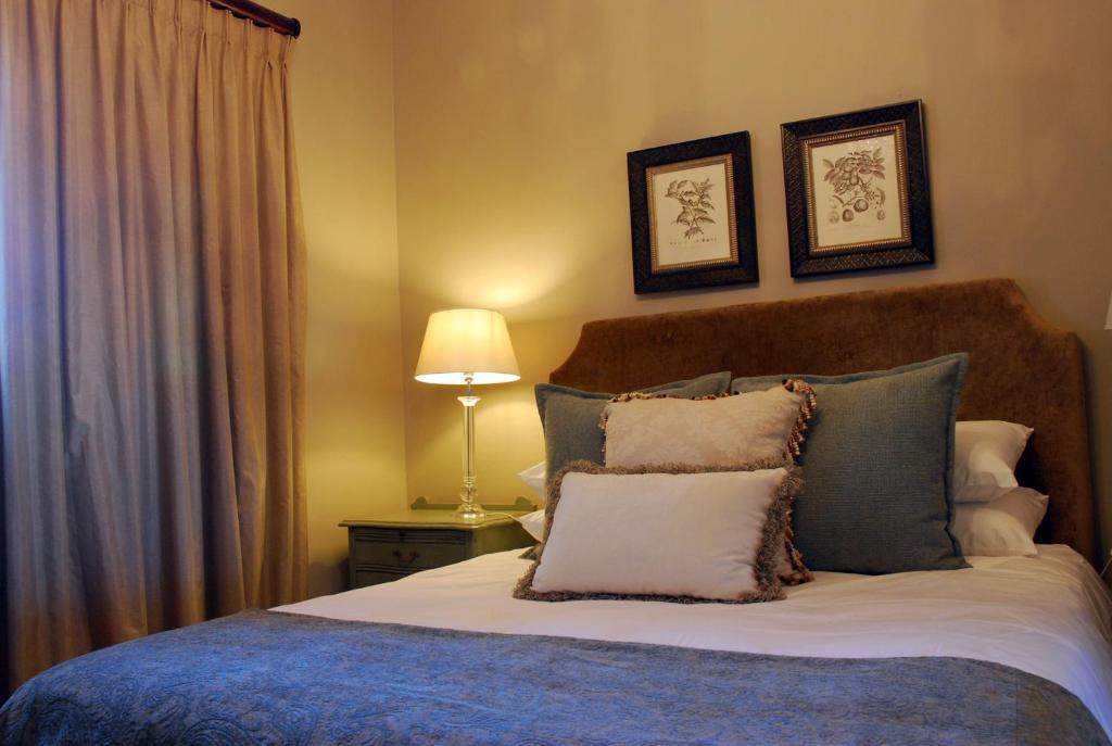 a bedroom with a bed with pillows and a lamp at Sneezewood Farm Bed&Breakfast and Self-Catering Cottage in Dundee