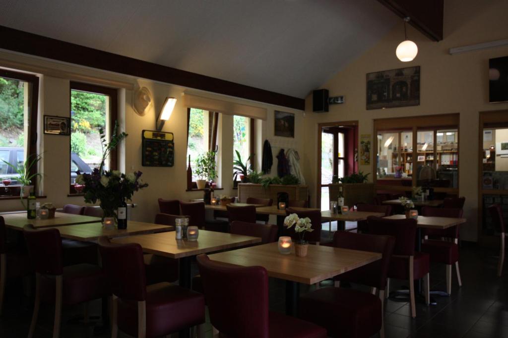 ein Restaurant mit Holztischen, Stühlen und Fenstern in der Unterkunft Camping Kautenbach in Kautenbach