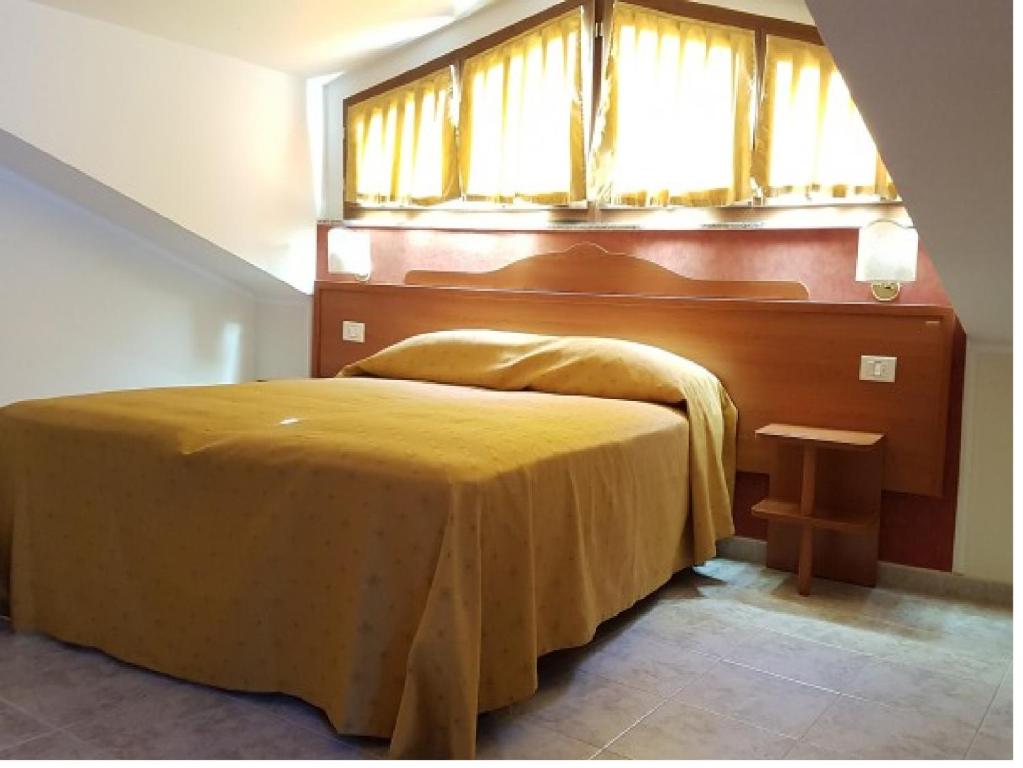 una camera con letto giallo e finestra di Hotel Dei Cappuccini a San Giovanni Rotondo