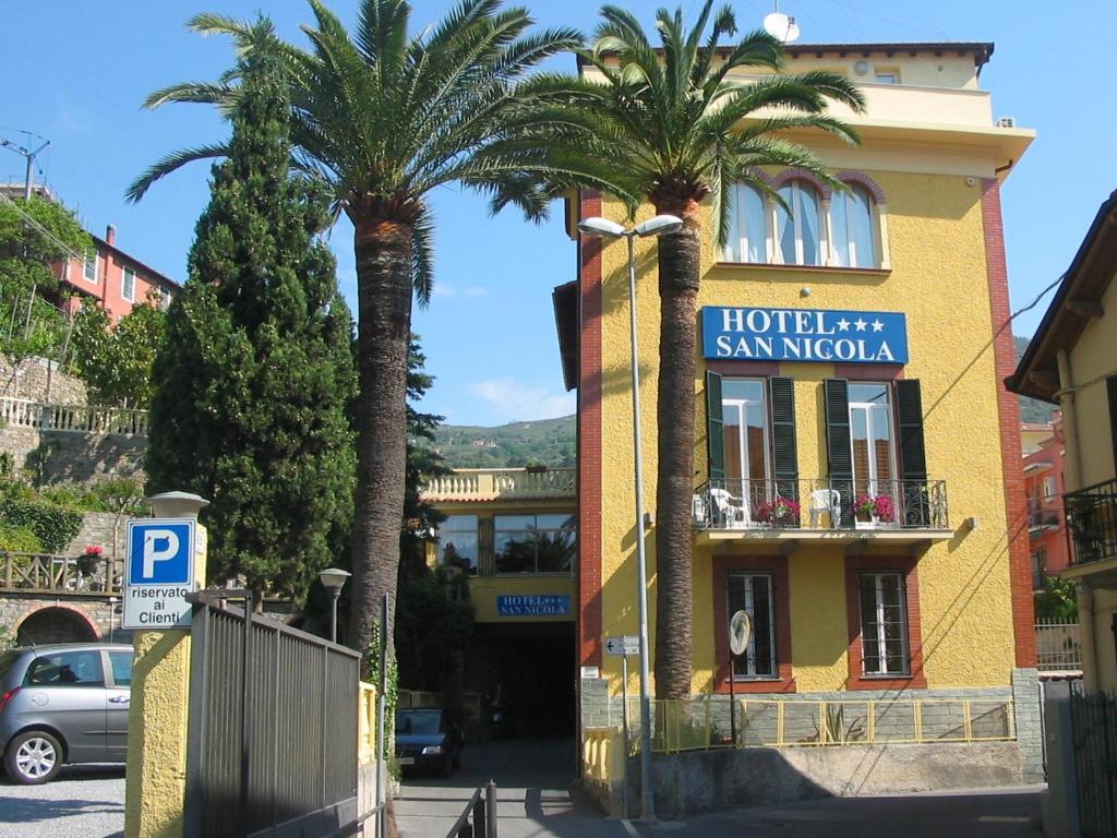 a hotel with palm trees in front of a building at Hotel San Nicola in Alassio