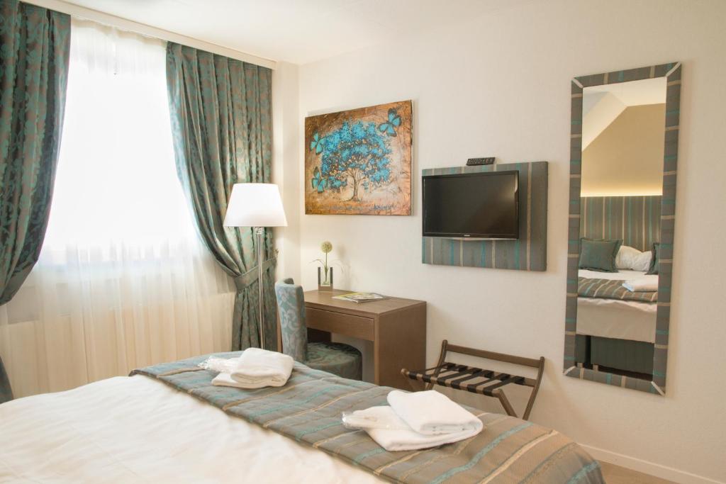 a hotel room with a bed and a mirror at Résidence de l'Ours in Lausanne