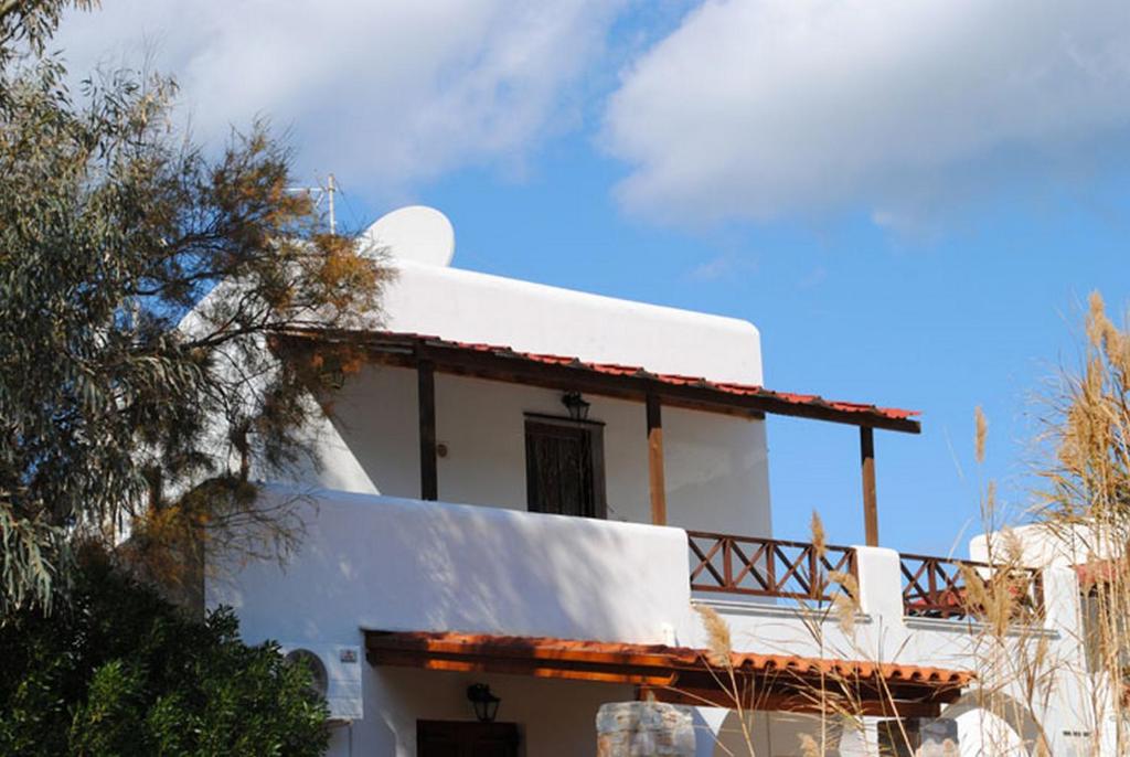 een wit huis met een balkon erop bij Akti Miaouli Holiday Home in Vári