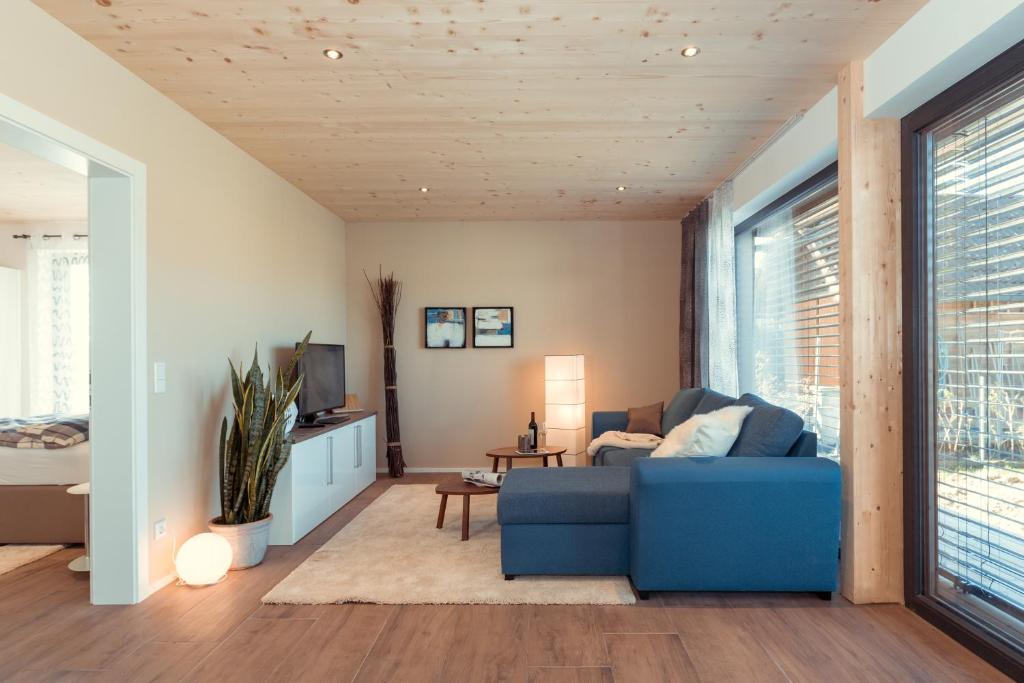 a living room with a blue couch and a tv at Simply Home Apartments in Ueberackern