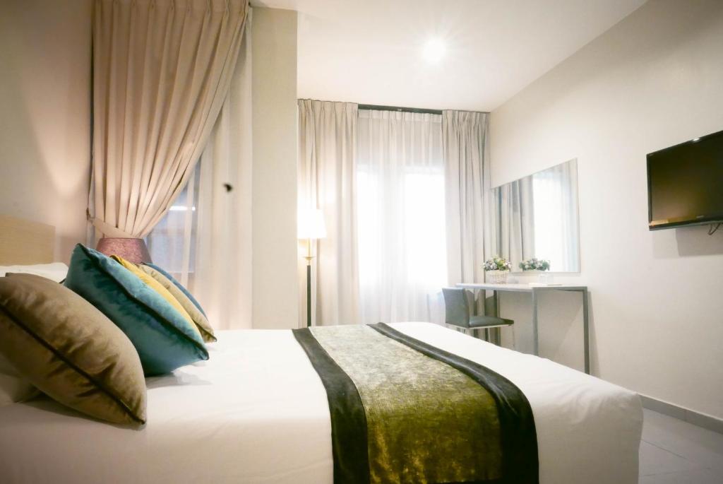 sypialnia z łóżkiem z poduszkami i oknem w obiekcie Country Inn w mieście Kulai