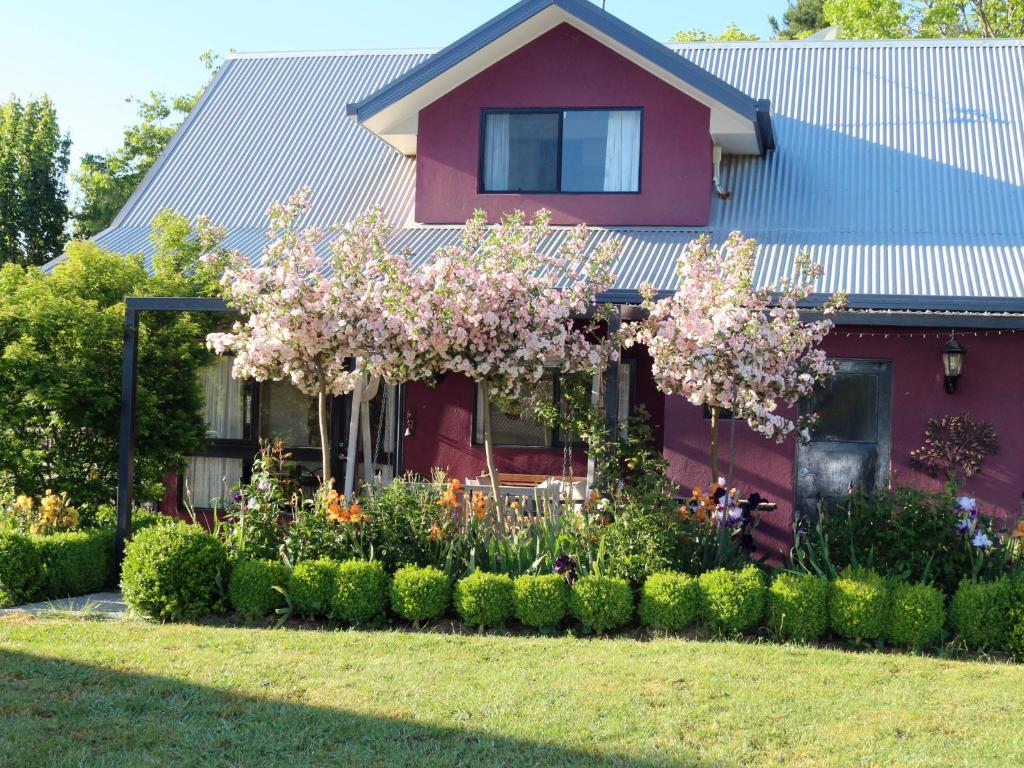 a red house with a garden in front of it at Magenta Cottage in Tumbarumba