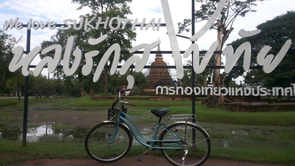 a bike parked in front of a sign in a park at Vitoonguesthouse2fanrooms & Aircondition in Sukhothai