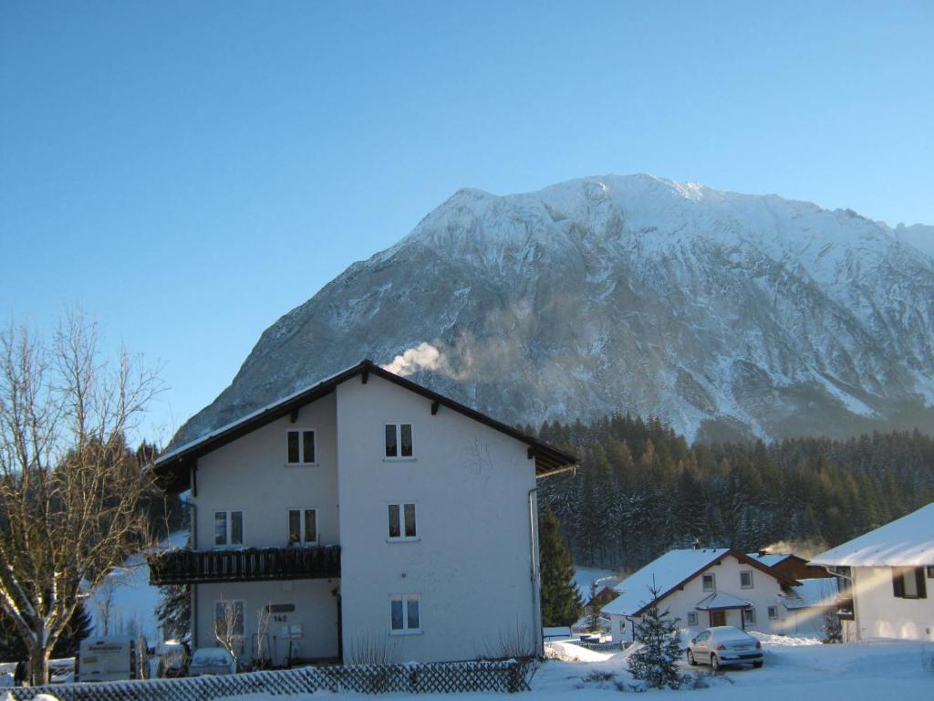 une maison blanche avec une montagne en arrière-plan dans l'établissement Haus Mundl, à Tauplitz