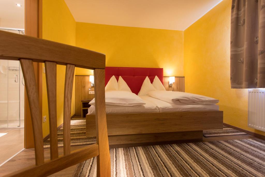a bedroom with a bed with a red headboard at Hotel Freiensteinerhof Superior in Sankt Peter-Freienstein