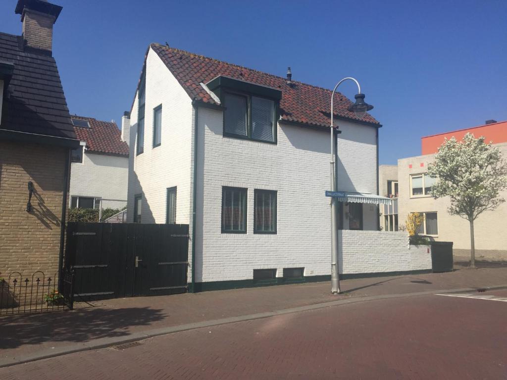 a white house with a red roof on a street at Appartement Lefferts in Zandvoort