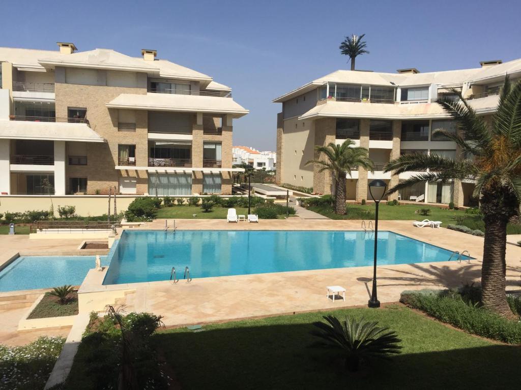 une piscine en face d'un grand bâtiment dans l'établissement Apartement Golf Resort, à Sidi Bouqnadel