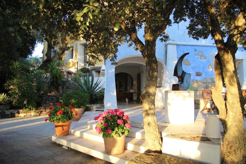 a courtyard with potted plants and trees in front of a building at Residenza di Campagna Seranile in Dorgali