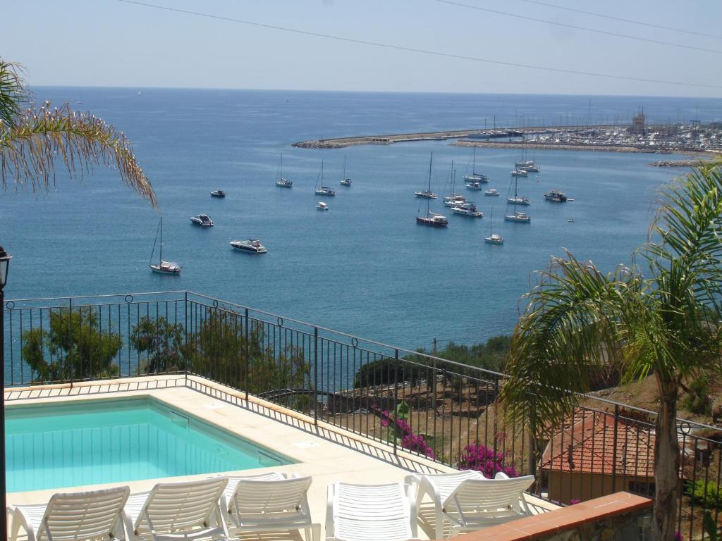 een zwembad met stoelen en uitzicht op een haven bij Villa del Mare Ligure in Santo Stefano al Mare