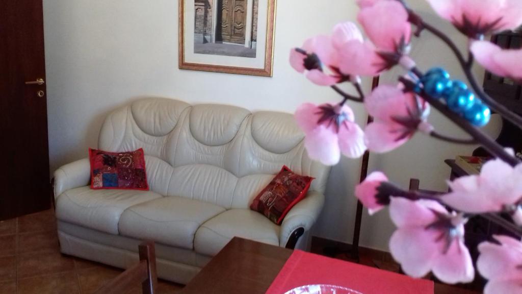 a living room with a white couch and pink flowers at Appartamento Corallo in Arona