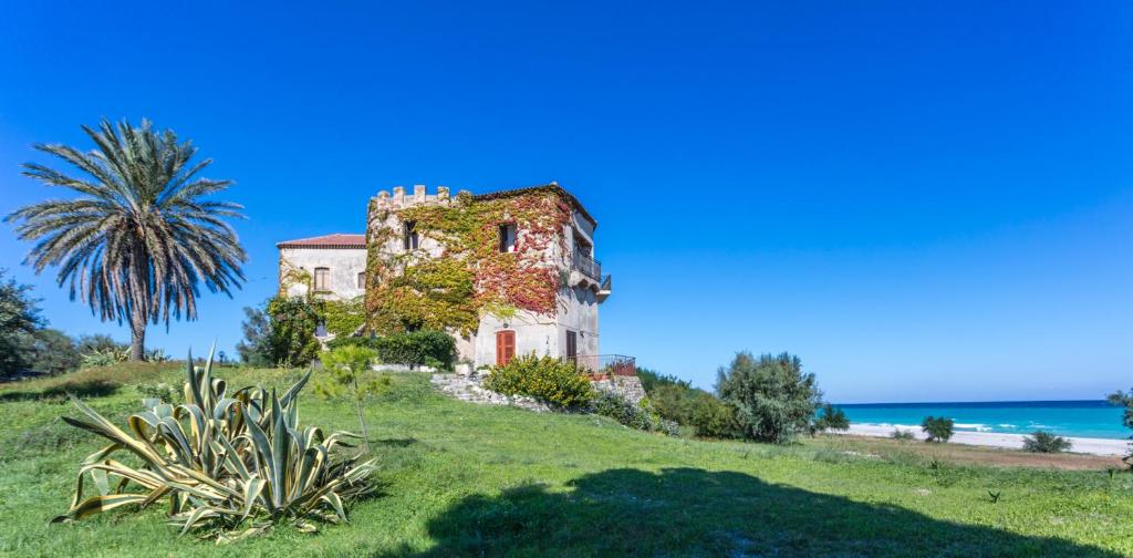 uma casa velha numa colina junto ao oceano em Torre S.Antonio em Santa Caterina dello Ionio