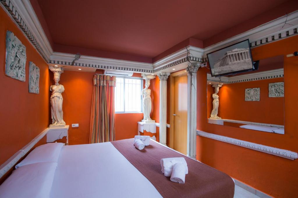 バレンシアにあるCasual Civilizaciones Valenciaのオレンジ色の壁のベッドルーム1室、ベッド1台(タオル付)が備わります。