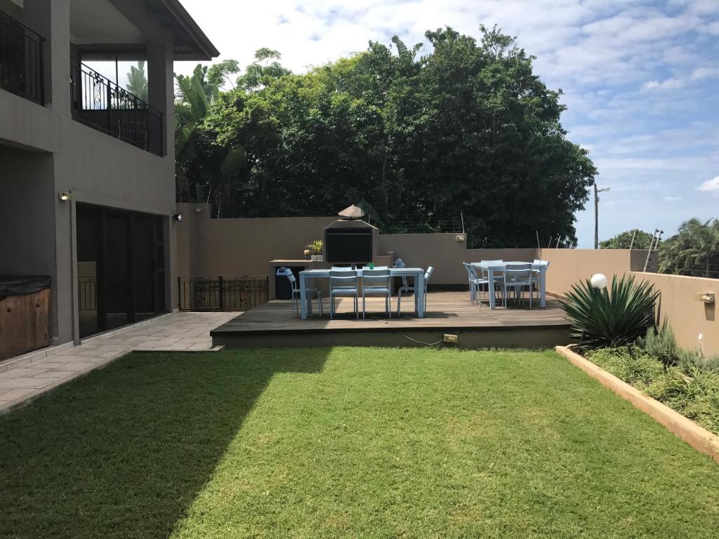 a patio with a table and chairs and a lawn at Hilken Lodge in Durban