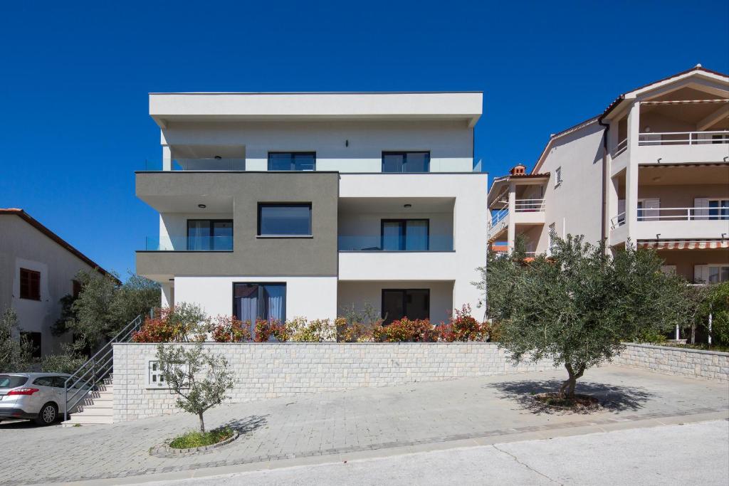 a large white building with trees in front of it at Lemechi Casa Girasole Apartments in Rabac