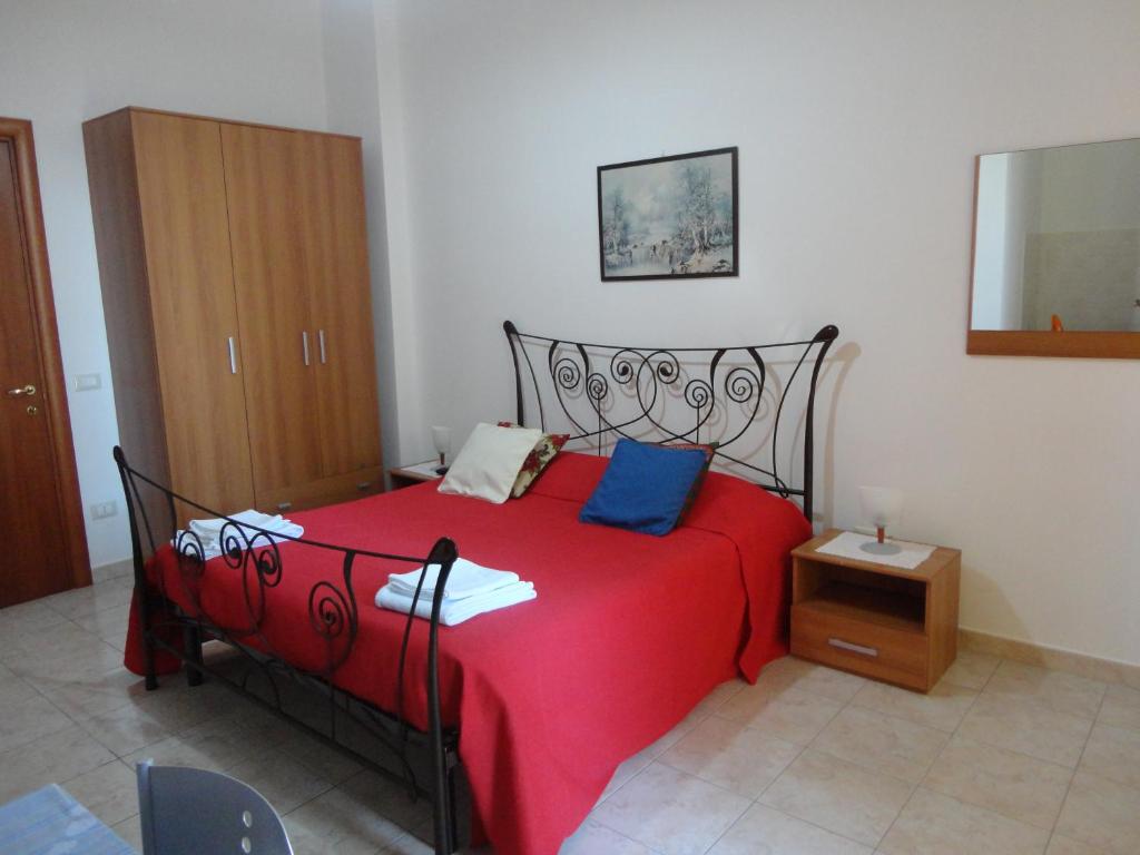 a bedroom with a red bed with a wooden cabinet at B&B Villa Teresa in Lecce